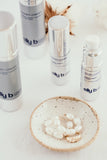 A group of Dream Cream bottles with a dish holding  pearl earings and a ring.