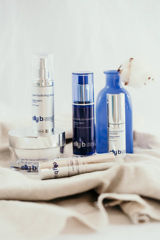 A group of elly b products placed on some material with a blue vase in the background.