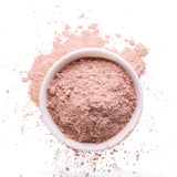 Pink clay mask spilling out of a jar onto a white background.