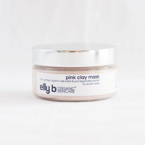 A jar of pink clay mask with a silver lid on a white background.